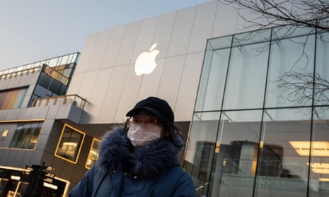 A woman in a face mask outside a closed Apple Store in Beijing