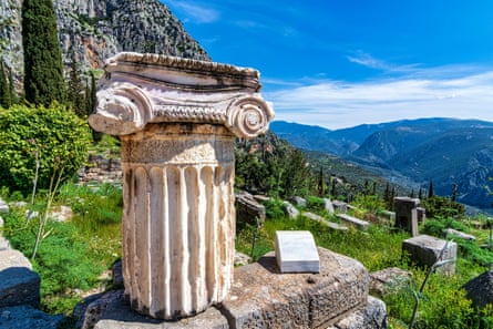 Ancient white Greek column on a green hillside in the sunshine