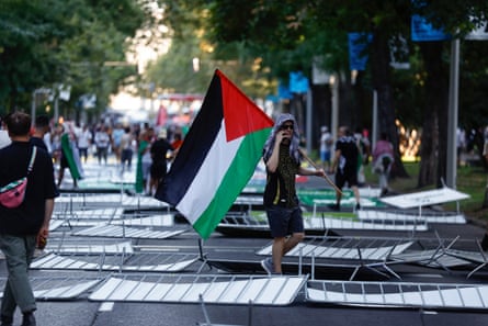 Demonstrators, some holding Palestinian flags, stand among knocked-down barricades.