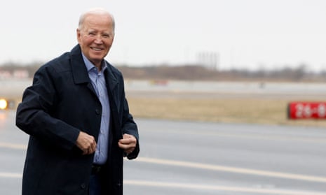 Older man in collared shirt and coat on tarmac, smiling.