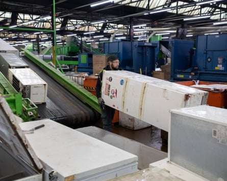 A man loads old fridges on to a conveyor belt