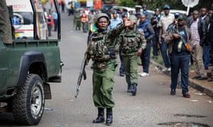 A Kenyan police officer tries to control the crowd outside the business complex in Nairobi on Wednesday, one day after an attack by militants.