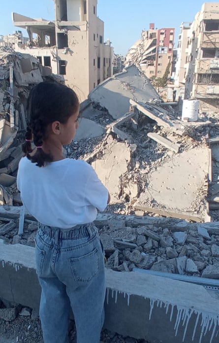 Sarah al-Sharif, nine, back to camera, looks out over the bombed out ruins of Gaza City