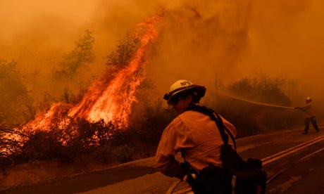 Firefighters spray water as flames push towards a road during the Windy Fire in the Sequoia National Forest near Johnsondale, California.