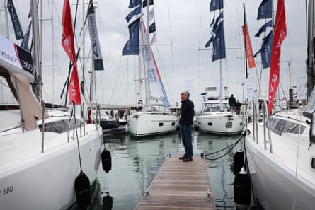 A man on a pontoon looks up at a moored sailing boat.