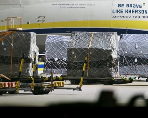 Wrapped freight on mobile pallets under a plane in Ukraine colours with the legend ’Be brave like Kherson’