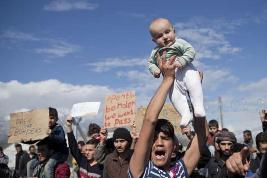 Stranded refugees and migrants protest in front of the wire fence that separates the Greek side from the Macedonian one.
