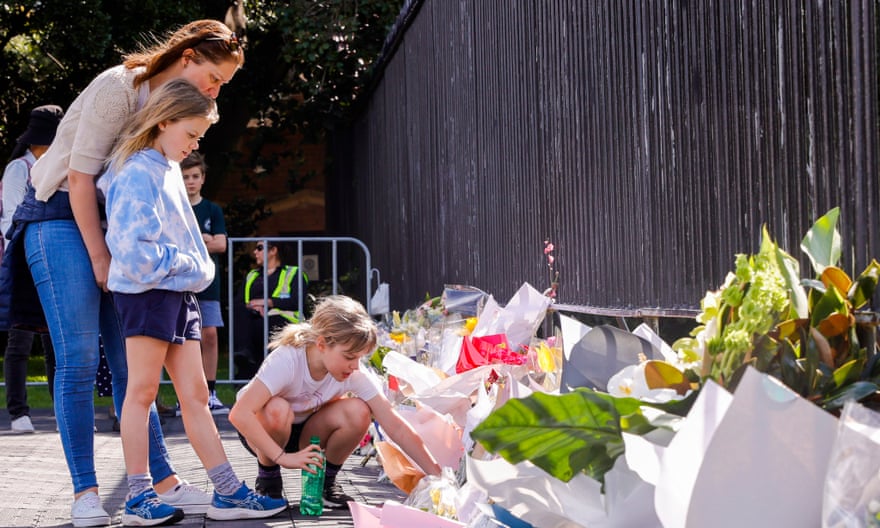 People watch floral tributes for Queen Elizabeth II at Government House in Sydney.