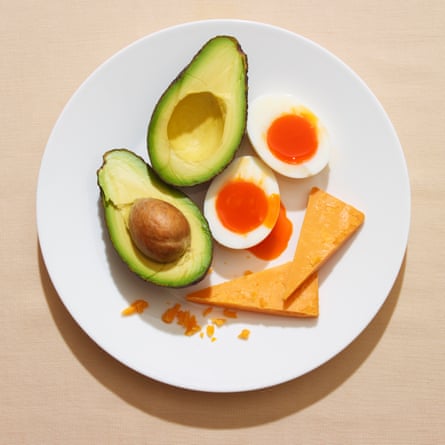 Halved avocado and egg on white plate against beige background