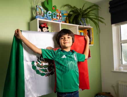 Diego Cornejo-Kersten in his bedroom wearing a green Mexico shirt and holding a Mexican flag behind him