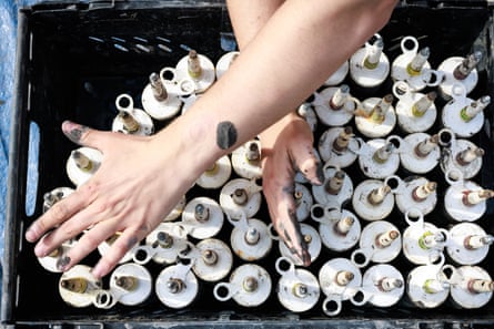 Dispensing tubes filled with a mix of seeds and fireclay powder are counted in preparation, ahead of low tide.