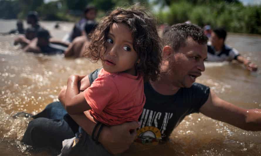Luis Acosta keeps a tight grip on five-year-old Angel Jesus as a caravan of migrants crossed into Mexico from Guatemala.