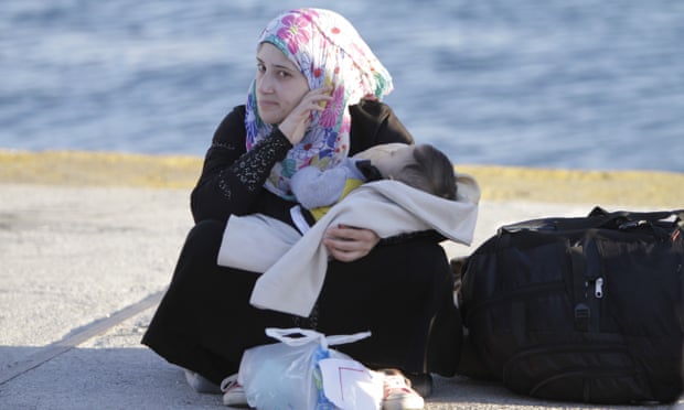 A refugee woman sits on the ground in Piraeus port.