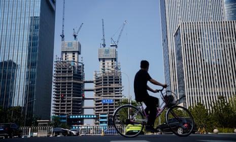 A man rides a bike along housing properties in Beijing, China