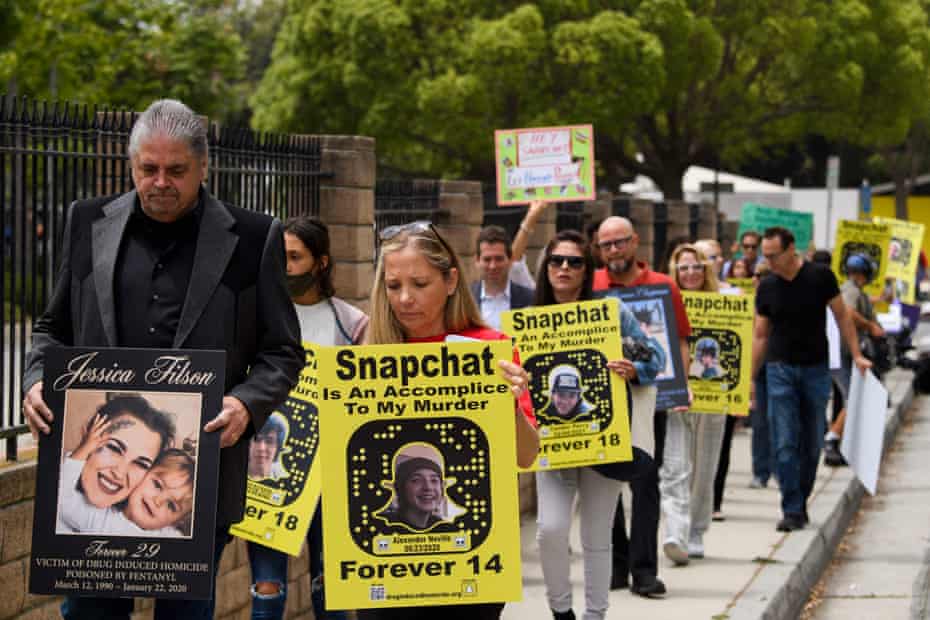 line of people hold placards saying 'snapchat is an accomplice to my murder' with pictures of young people who died