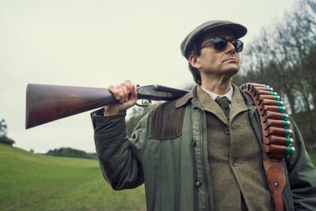 David Tennant as Lord Tony Baddingham in Rivals, with a shotgun over his shoulder, wearing a flat cap and tweed jacket