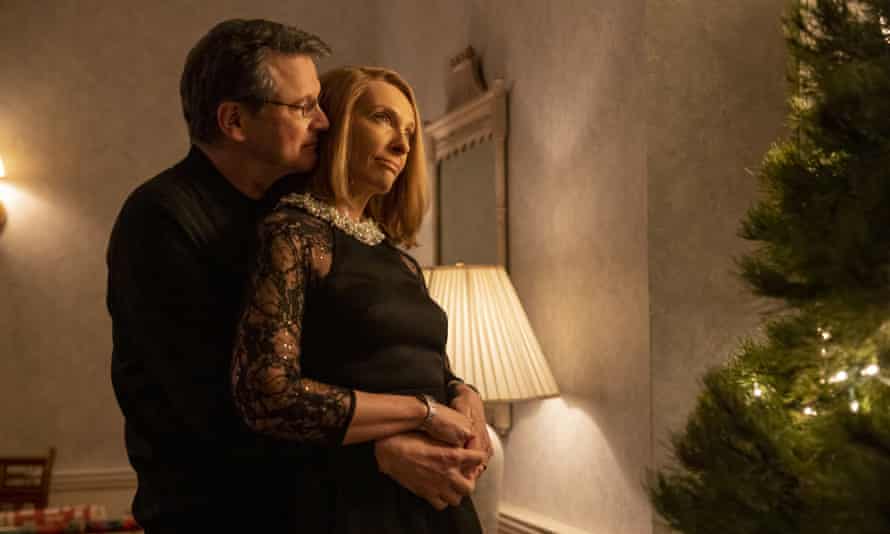 A man embraces a woman from behind in a dimly lit room