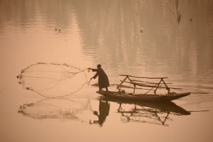 A fisher casts his net on a foggy autumn morning in Kashmir, India