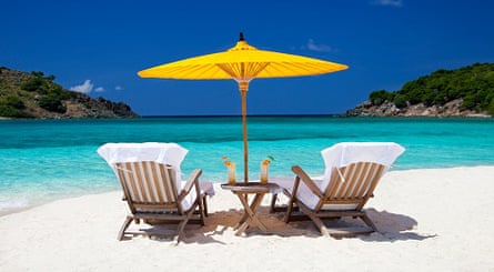 Teak steamers under yellow umbrella on a beach in the Caribbean