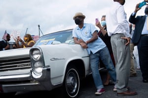 Duluth, US: a man leans on a classic car as he listens to Joe Biden during a drive-in rally at Infinite Energy Center, Georgia
