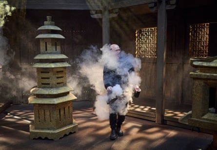 A member of the stage production staff spreads dry ice around the stage area before the start of Act three