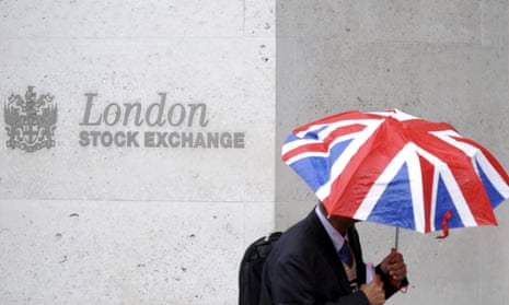 A worker shelters from the rain as he passes the London Stock Exchange