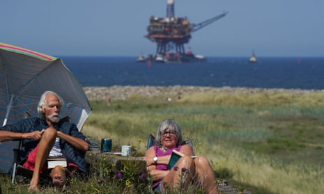Couple picnicking with North Sea oil platform in distance