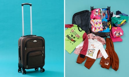 An open suitcase full of children’s clothes.