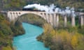 Steam train on Solkan bridge over turquoise water