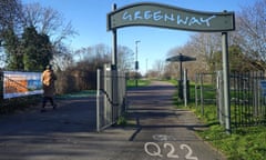 The junction of the Greenway and High Street South in Newham: a path and cycleway stretches into the distance under a sign which reads Greenway; there are strips of grass and small trees to either side.