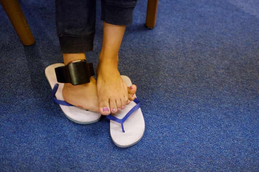 woman’s feet in flip flops with ankle monitor