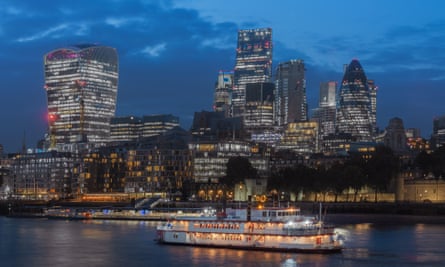 A boat passes by the City of London at night.