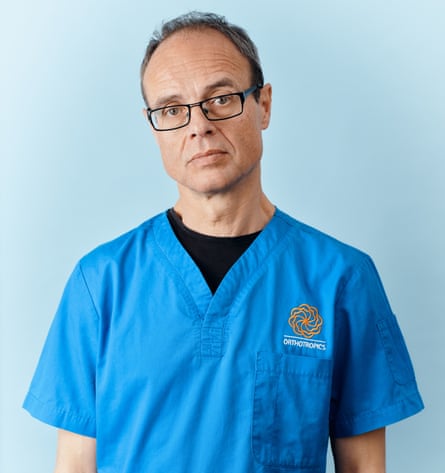 Orthodontist Mike Mew in his blue scrubs, photographed at home in Tunbridge Wells for The Guardian Saturday Magazine, April 2025