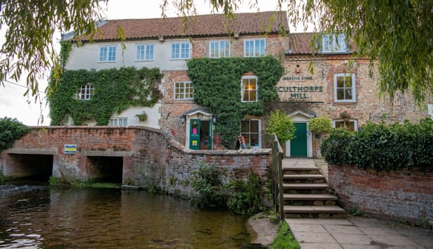 Vine-clad Sculthorpe Mill hotel sits on a small bridge crossing the shady River Wensum