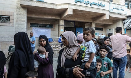 Woman hold children in their arms as they queue in Gaza to be vaccinated
