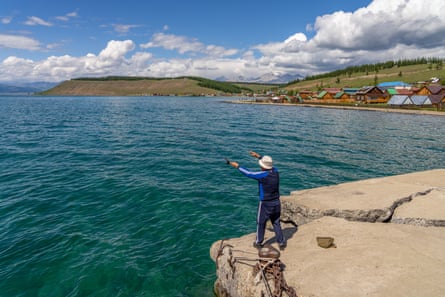 Bir adam Moğolistan'daki Hovsgol Gölü'nün kuzey kıyısındaki Hankh köyündeki bir iskeleden balık tutuyor.
