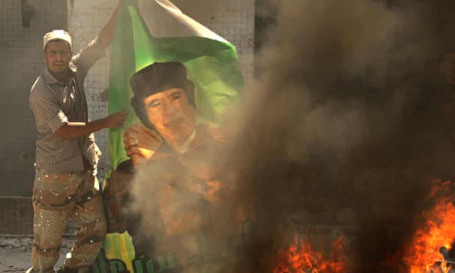 A Libyan rebel burns a poster of Muammar Gaddafi in Tripoli in 2011