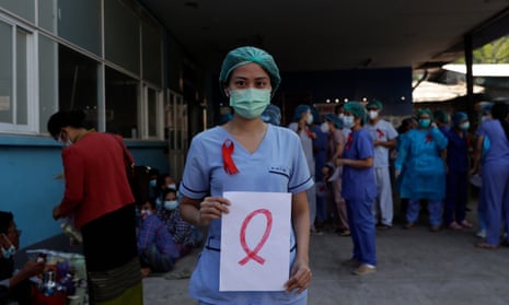 A medical staff member holds a red ribbon sign as a symbol of resistance at Central Women’s hospital in Yangon