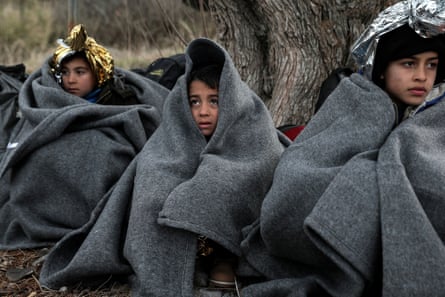 Children huddle under blankets after arriving by dinghy on a beach on Lesbos.