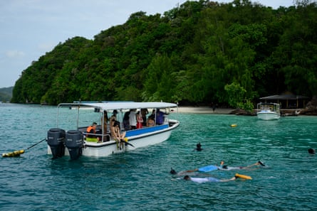 Turistas chinos desembarcando de un barco para hacer esnórquel en el parque de la isla Ngermeaus. Poco antes de entrar al agua, se les arrojó una especie de tiburón burley para atraer a los tiburones de arrecife y a varias especies de peces, mejorando así la experiencia submarina.