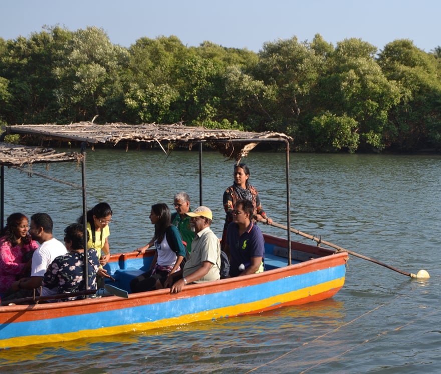 A woman paddles a brightly painted pleasure boat along a river