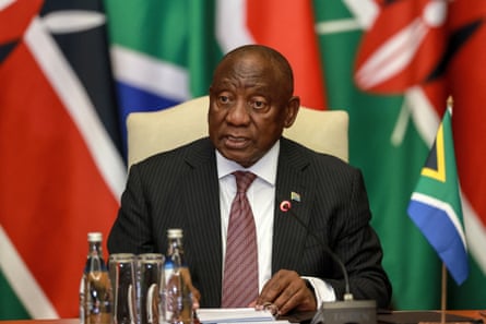 South Africa’s president, Cyril Ramaphosa, sits in front of various flags