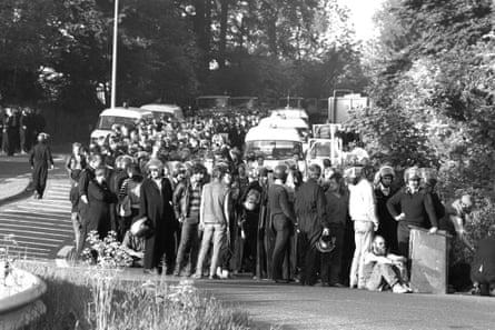 A crowd of uniformed officers and plain clothed people stand along the side of the road.