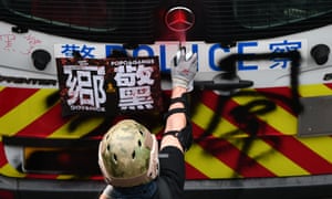 A protester spray paints graffiti on a police van