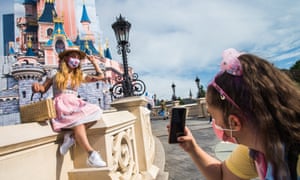 Visitors wearing protective face masks take pictures on the day of the official reopening of the Disneyland Paris theme park in Marne-la-Vallee, near Paris, France, 17 June 2021.