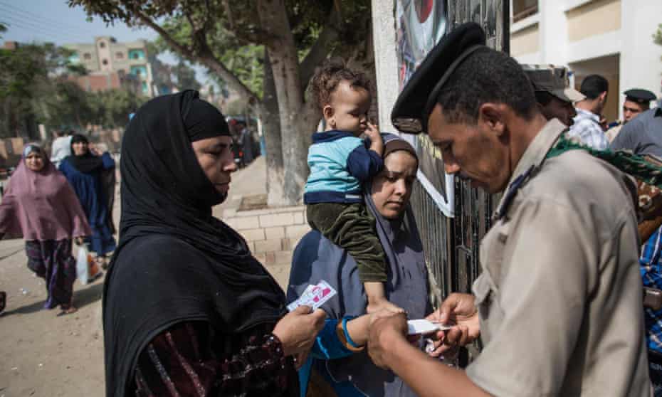 Egyptian security forces check documents of voters outside a polling station