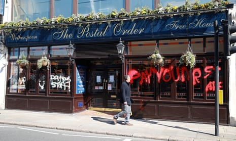 A man looks at graffiti on a JD Wetherspoon pub in Crystal Palace, south-east London, saying 'Pay your staff'.