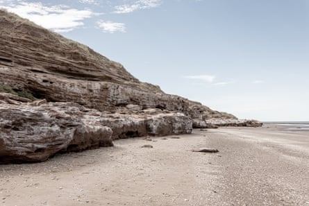 A rocky cliff sweeping down to a sandy beach 