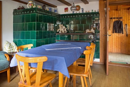A large green ceramic oven in the corner of a room with a wooden table and chairs in front of it