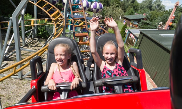 Two young girls sit at the front of a rollercoaster, specifically for younger riders, at Gulliver's Land, Milton Keynes, UK.